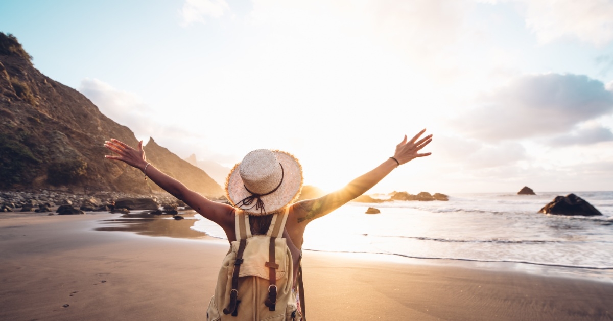 woman with arms up at beach