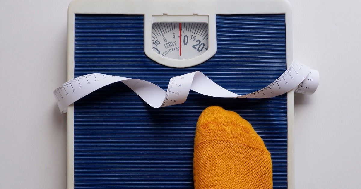 person with socks getting on weight scale