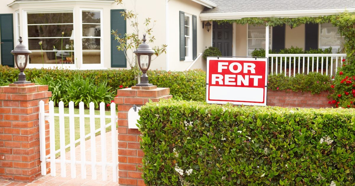 A suburban house with a For Rent sign in the front yard. 