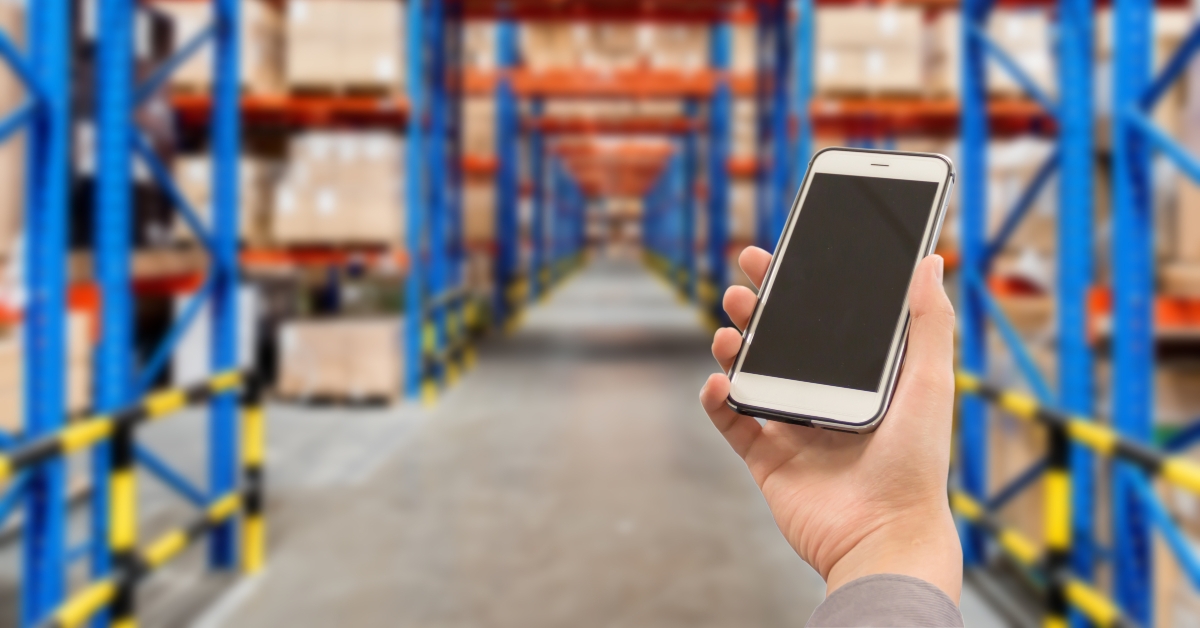 right hand using smartphone with blank screen on warehouse