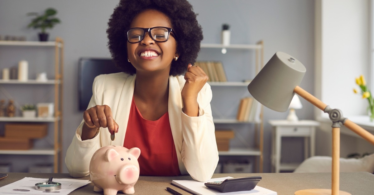 african american woman putting coins in piggy bank