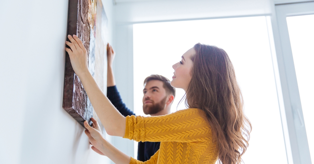 couple hanging picture on the wall