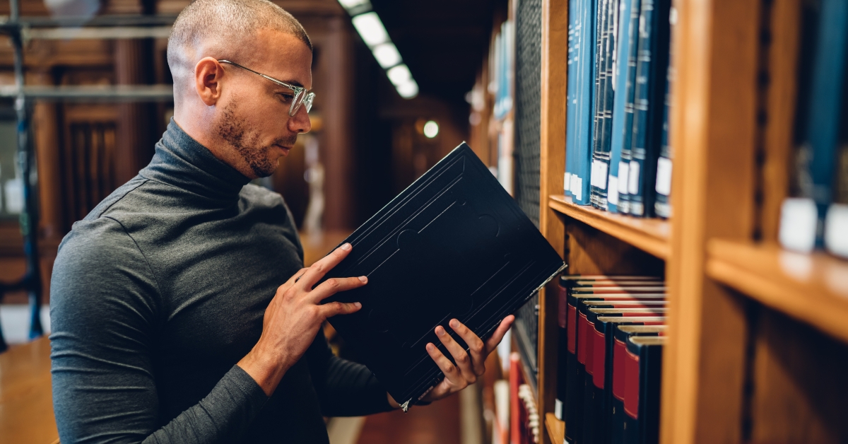 student standing near bookshelves checking literature
