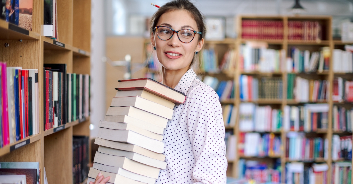 woman with a stack of books in library