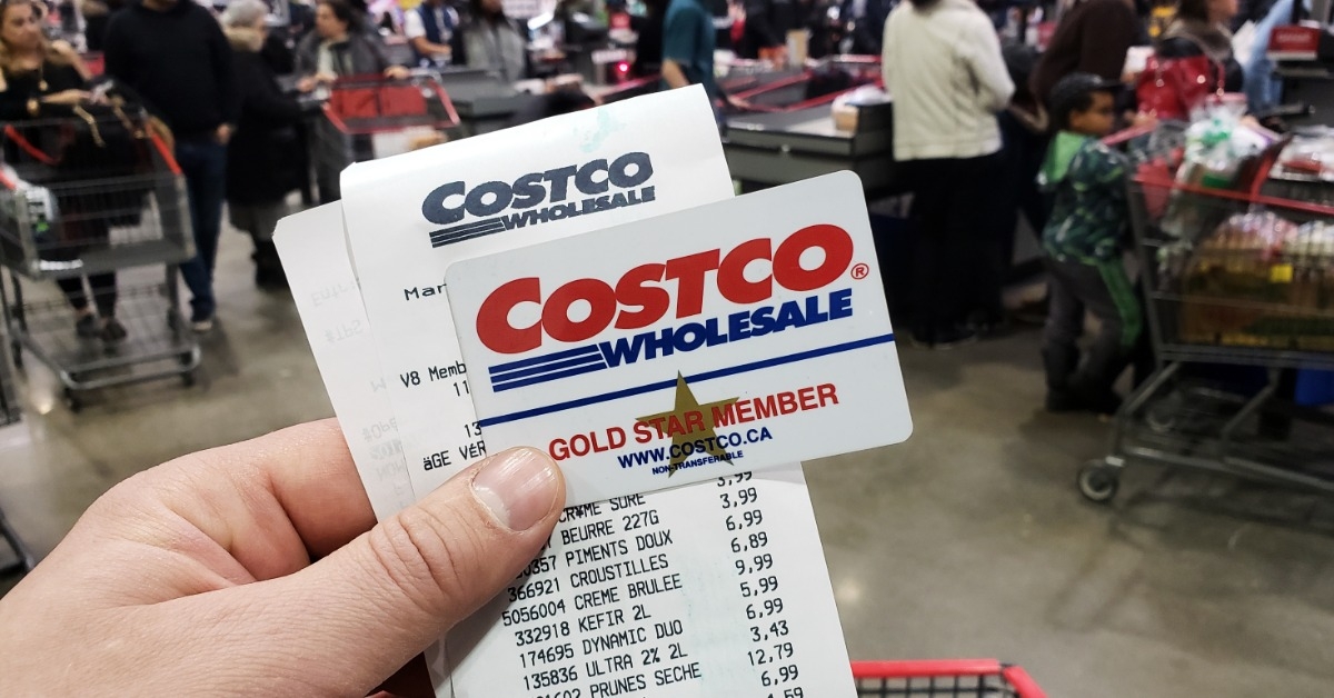 man holding costco wholesale membership card with receipt in store