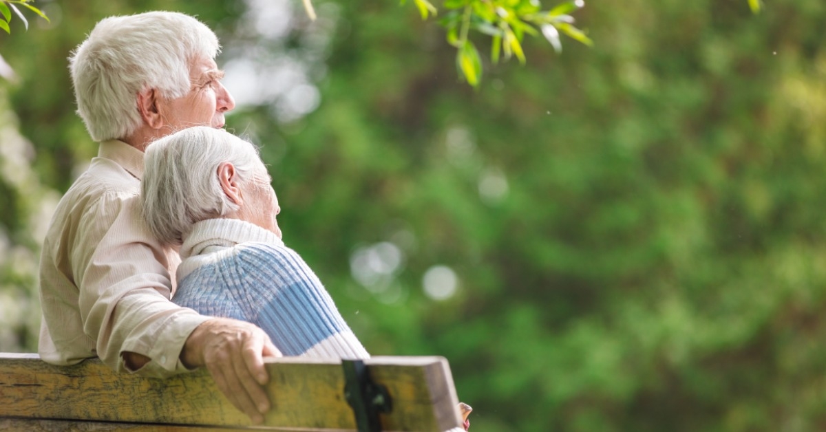 senior couple sitting on bench in park