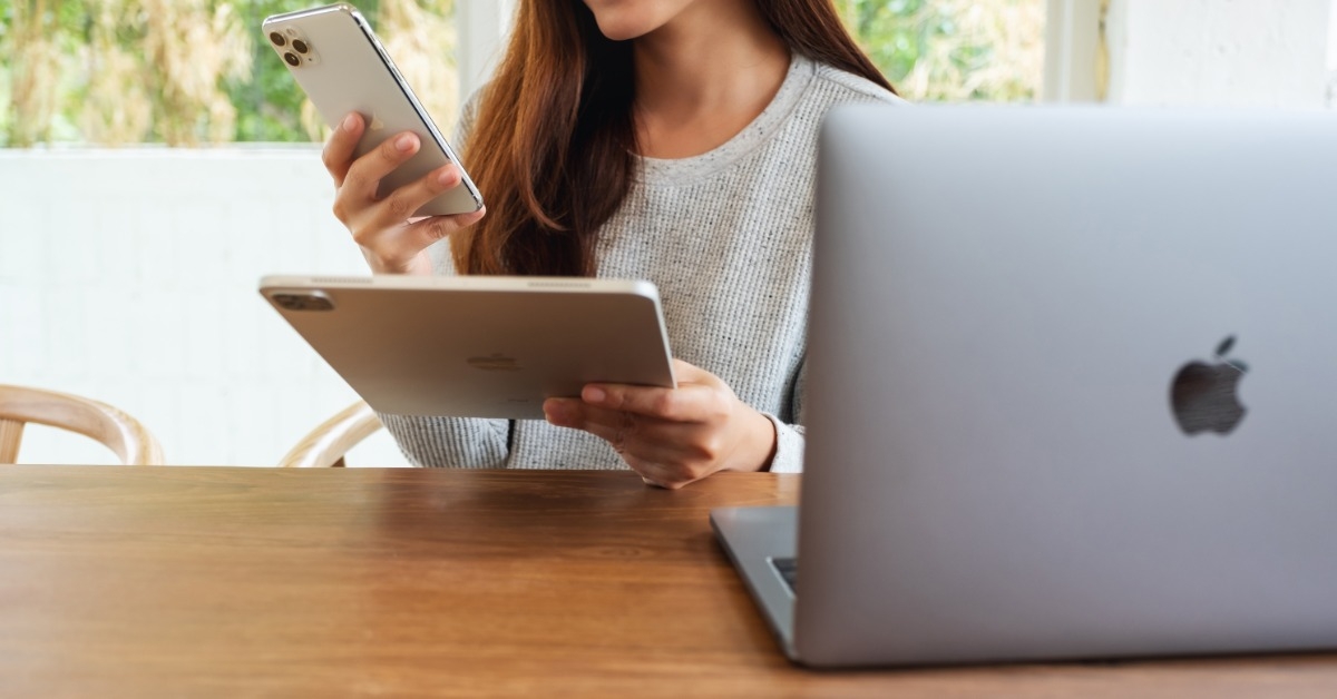woman using laptop iphone 11 and ipad
