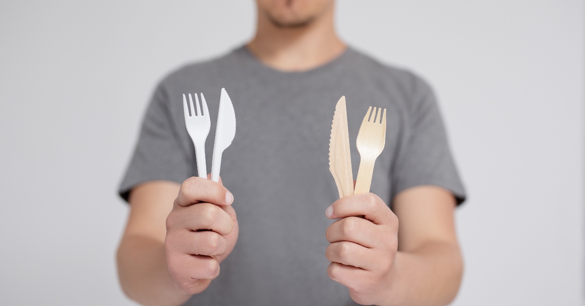 man comparing plastic and wooden forks and knives