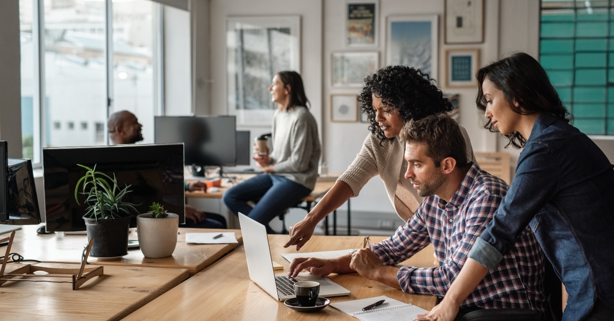 three young designers using a laptop together at work