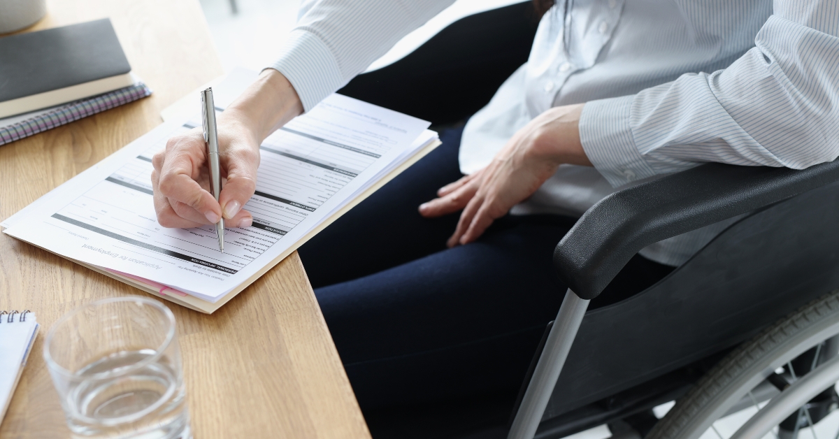 disabled woman in wheelchair filling out application form