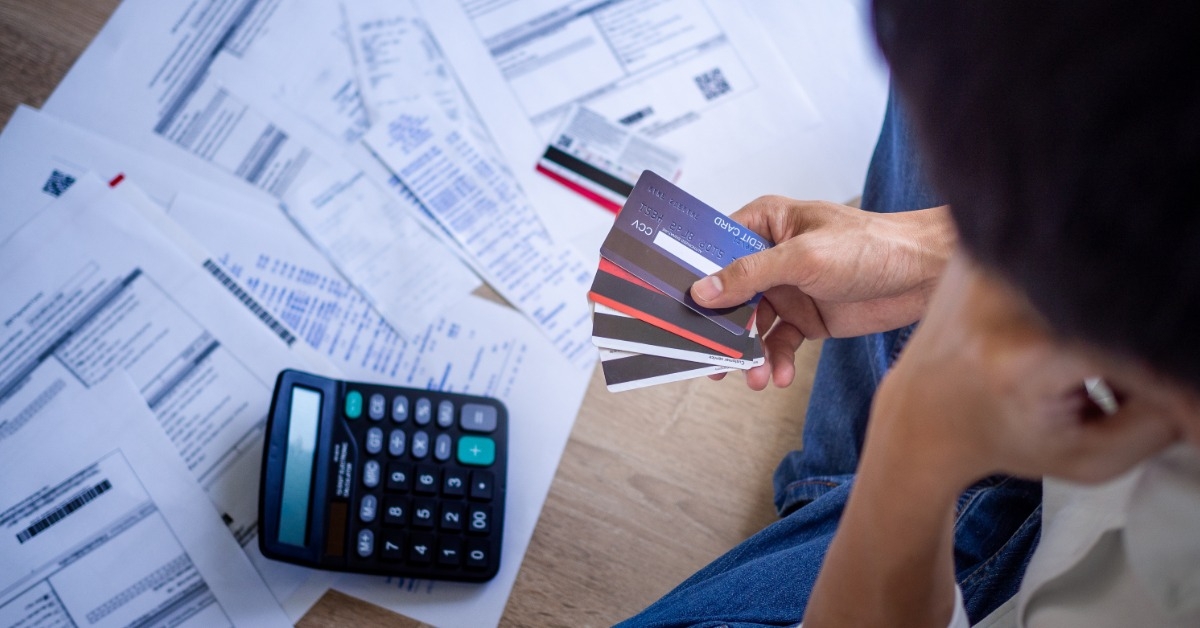 man holding credit cards in hands with documents in background