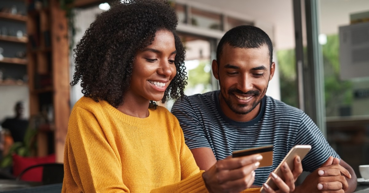 happy african american women holding card and smartphone in hands