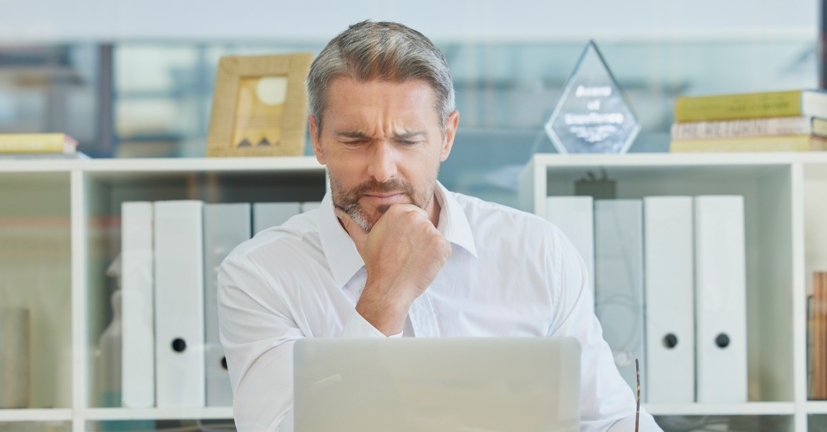 Confused man looking at laptop
