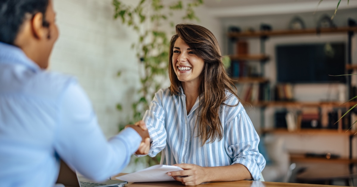 female employee in workplace shaking hands with man