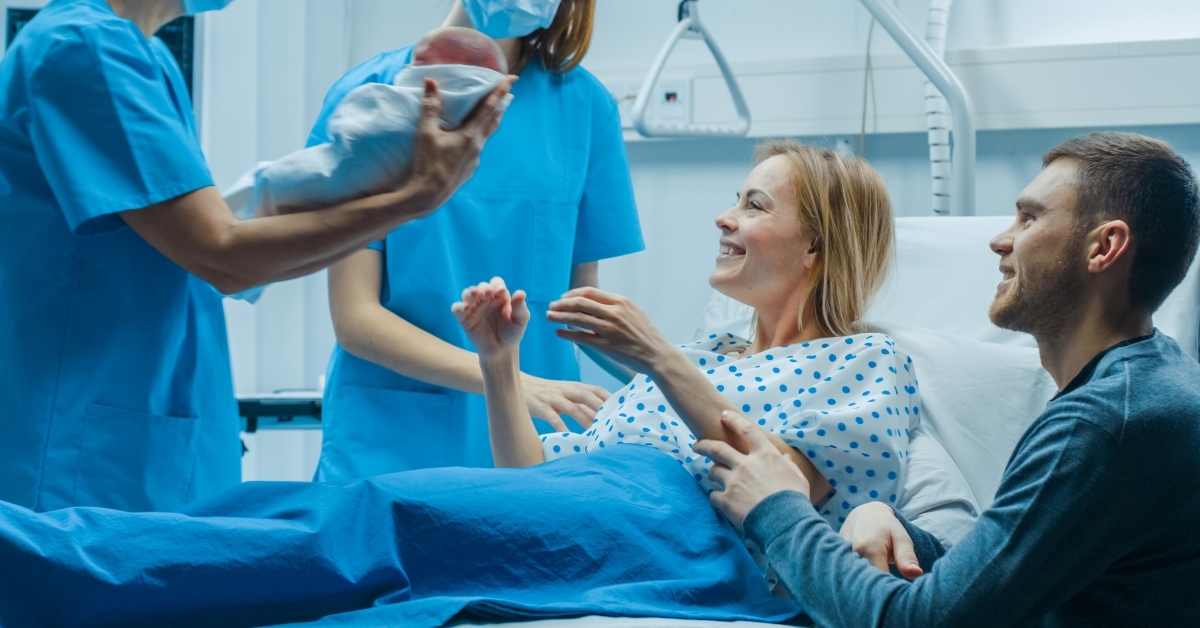 midwife gives newborn baby to a mother to hold