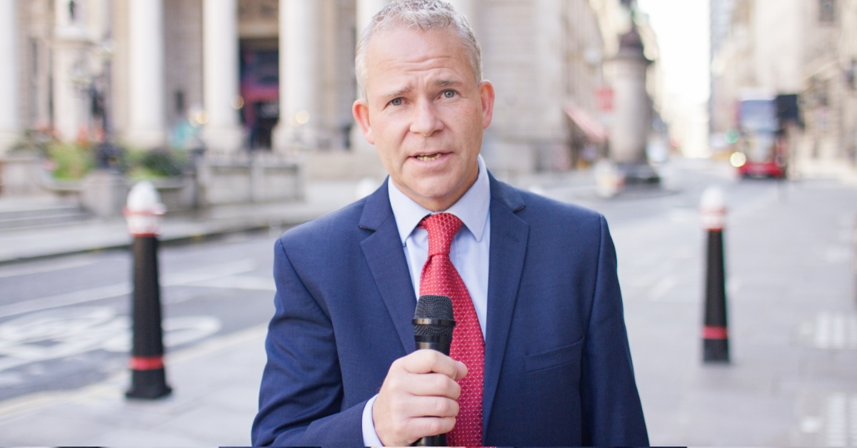 middle aged news reporter in suit holding mic in street