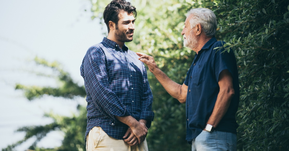 elderly man talking with a young man outside