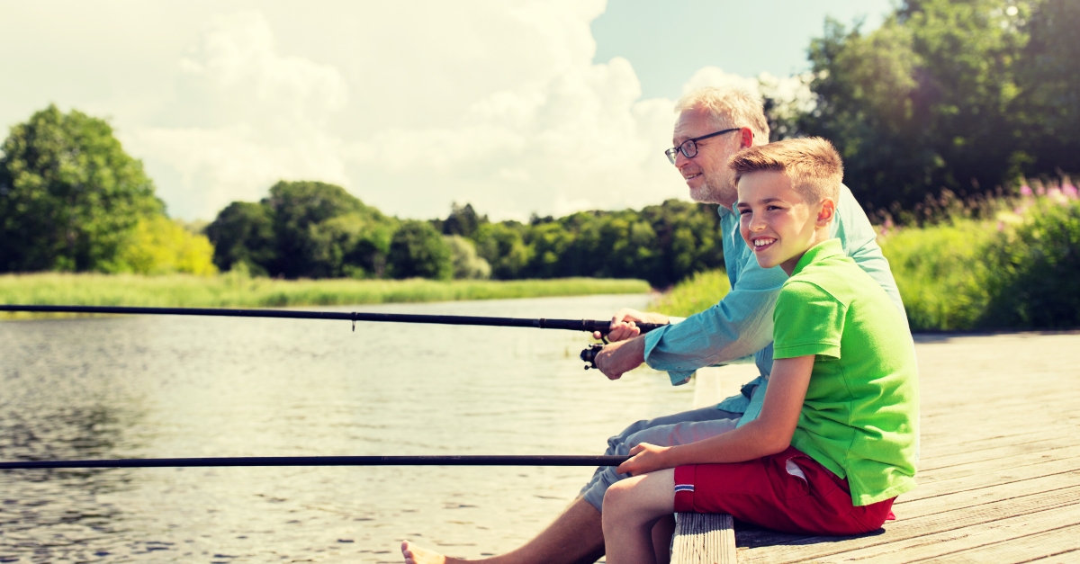 happy grandfather and grandson with fishing rods