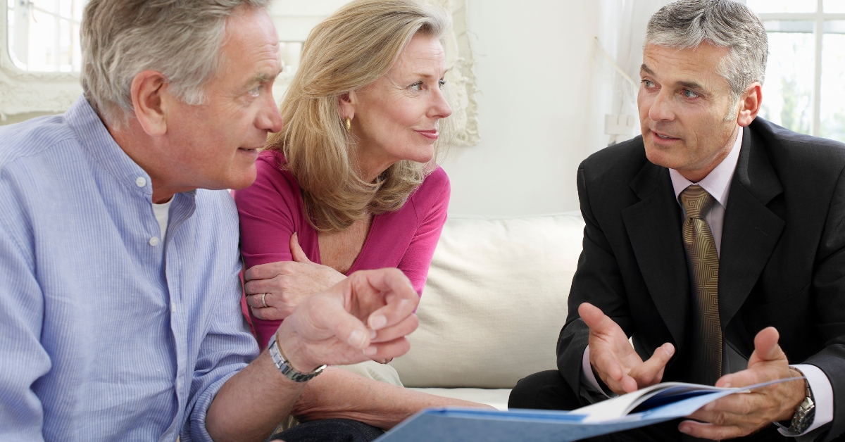mature couple sitting on sofa with financial advisor