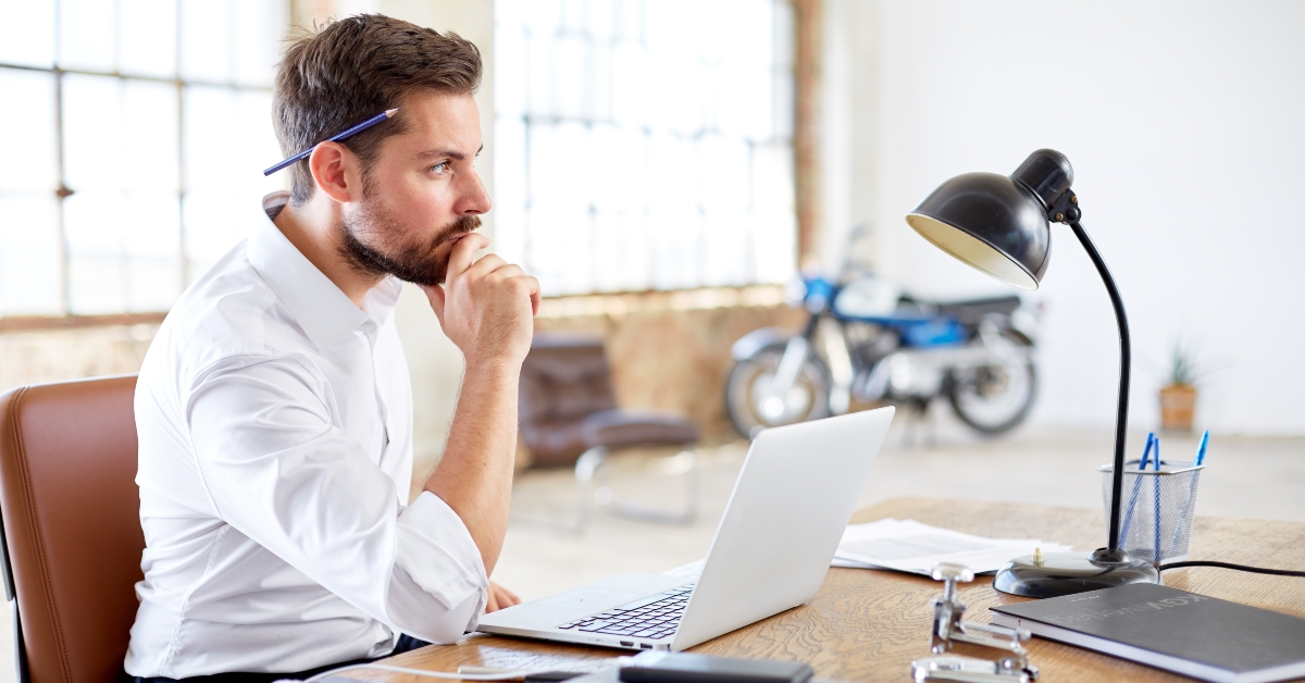 businessman with laptop and pencil on his head
