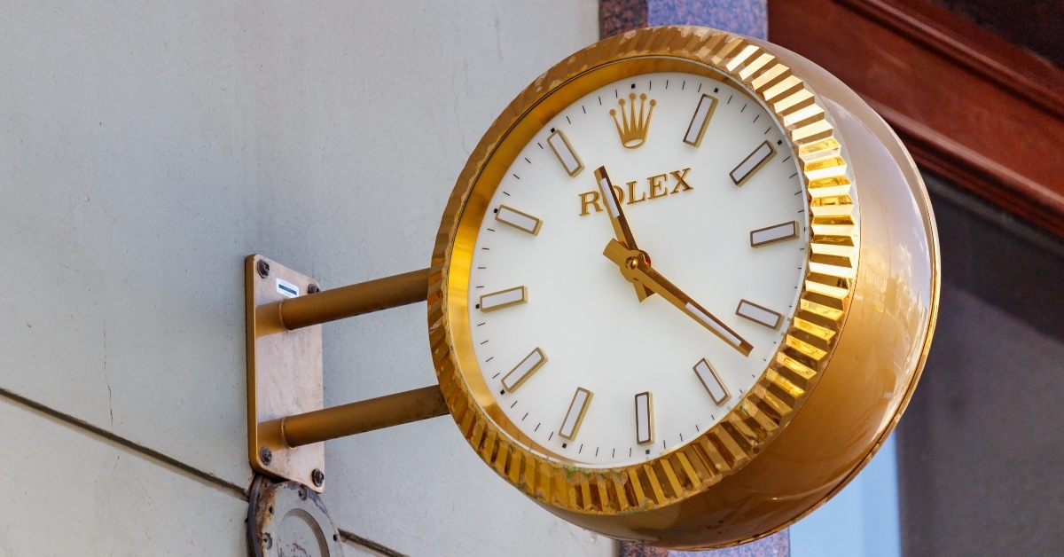 analogue street clock Rolex in golden case hanging on a wall