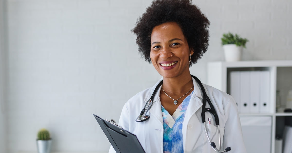 african american doctor wearing overalls with stethoscope holding headboard in hand