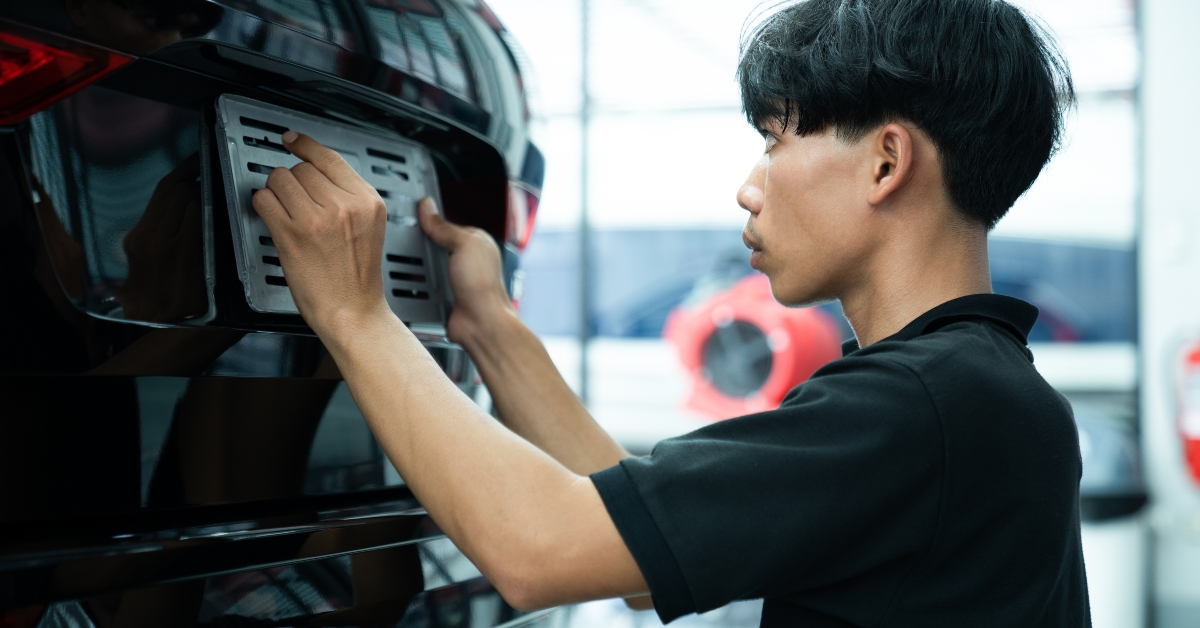 man installing the license plate of a car