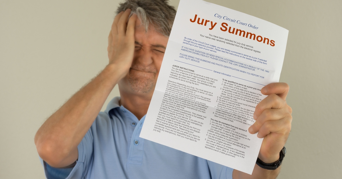 upset man holding out his hand to show the jury duty summons 