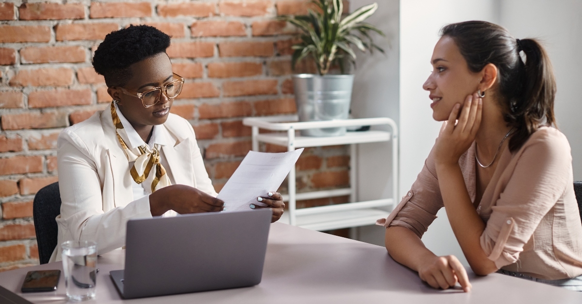 businesswoman reads resume of female candidate during job interview