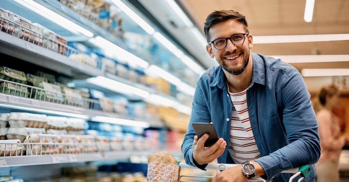 man using mobile phone app while buying groceries