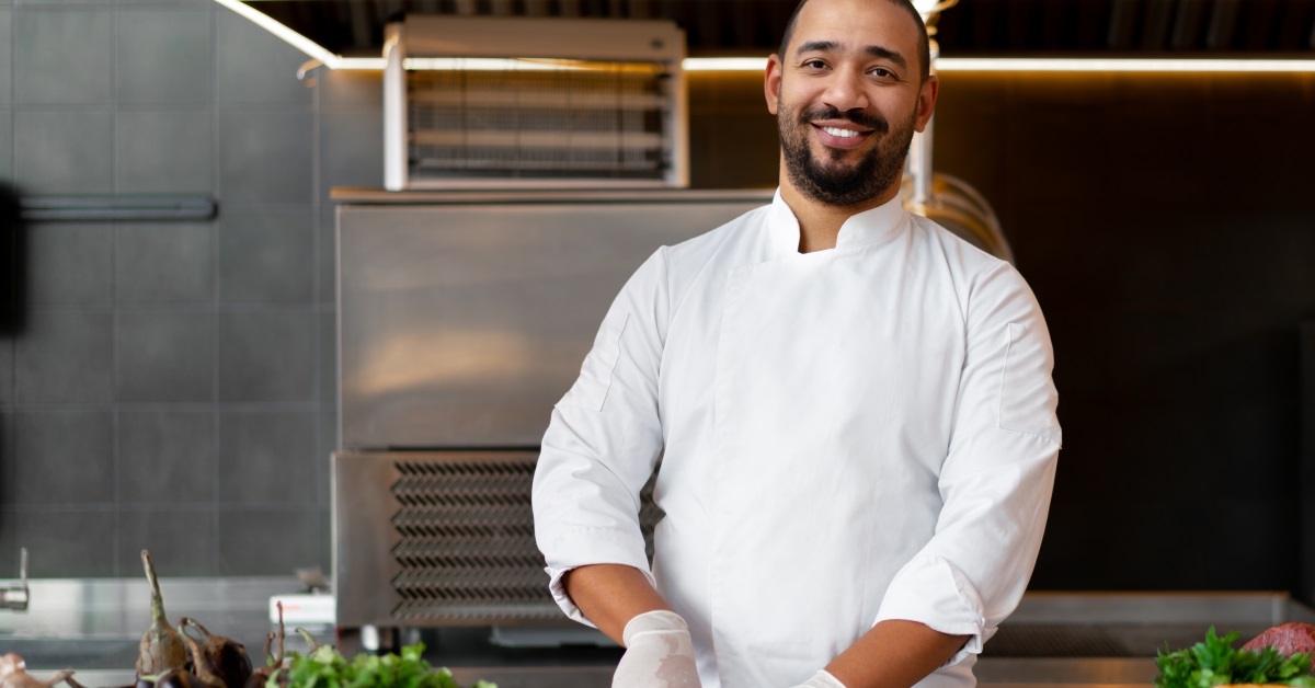 young happy chef chopping vegetables in kitchen