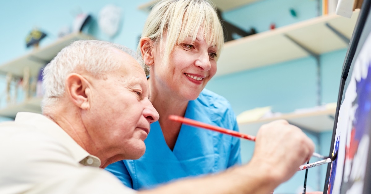 senior man and nurse painting together