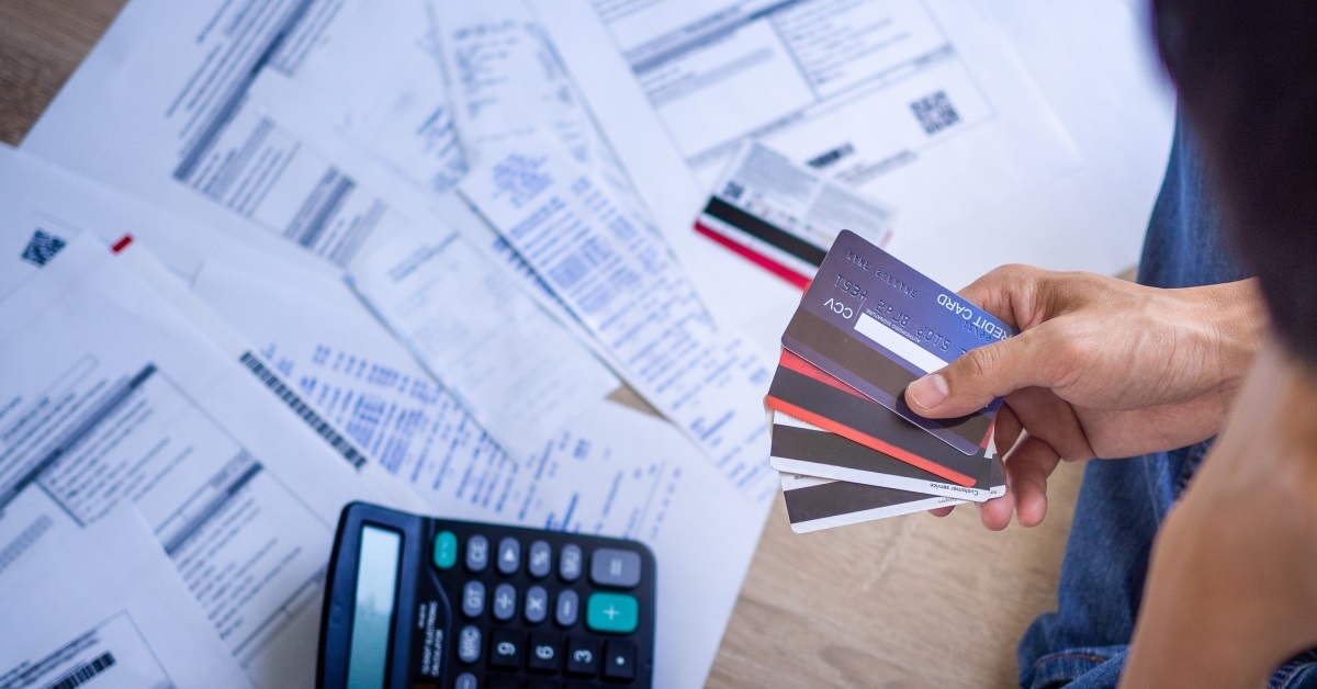 man holding credit cards in hand with calculator and papers in background