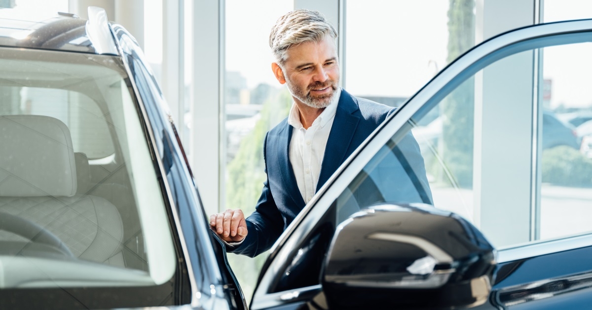 handsome senior man in suit getting into a car