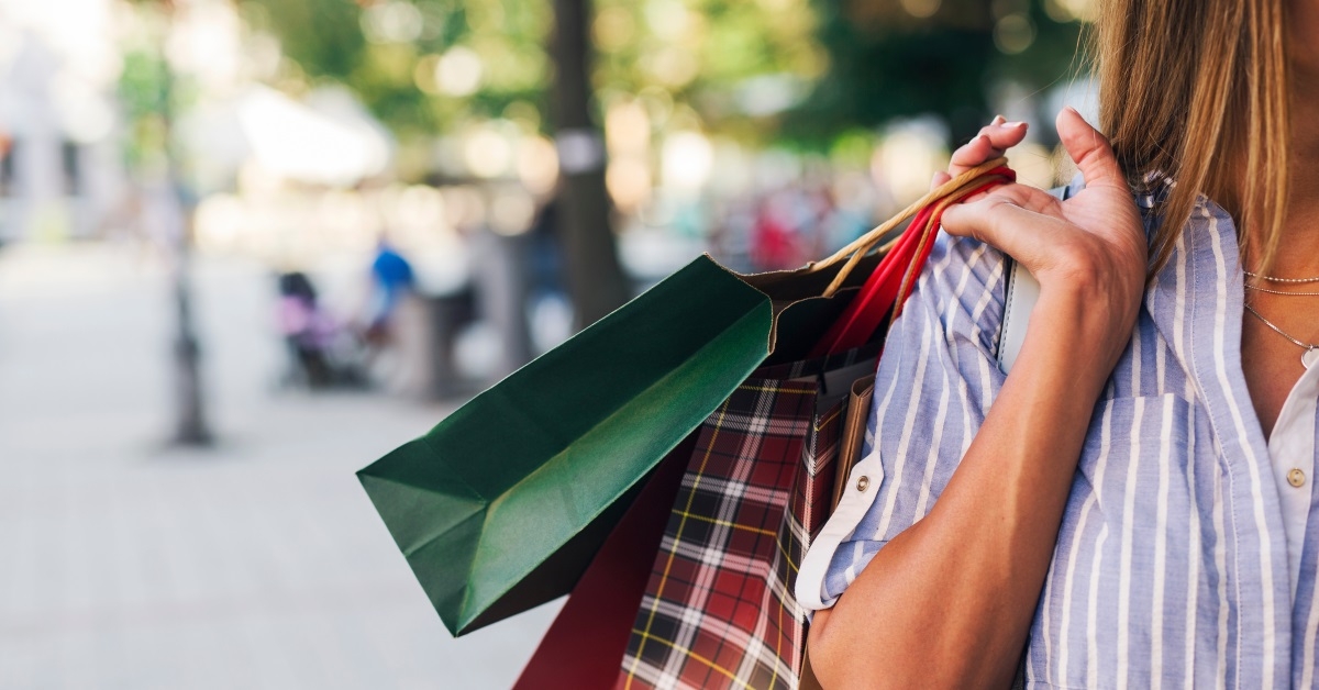 pretty woman holding shopping bags standing in the street