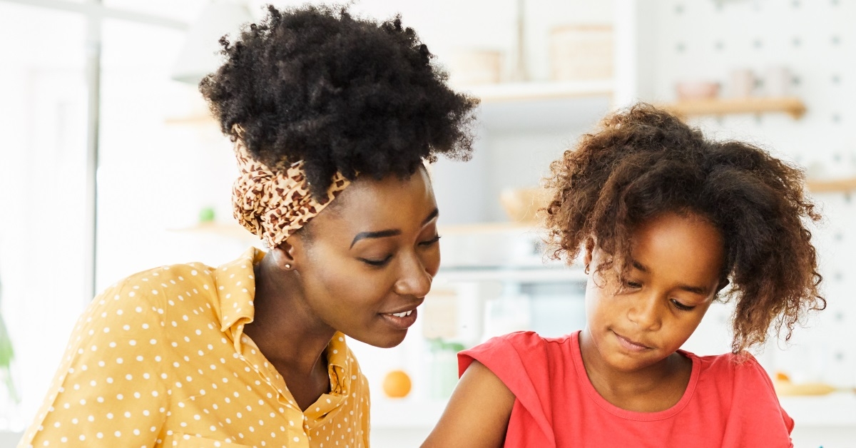 african american child is being supervised while doing their homework