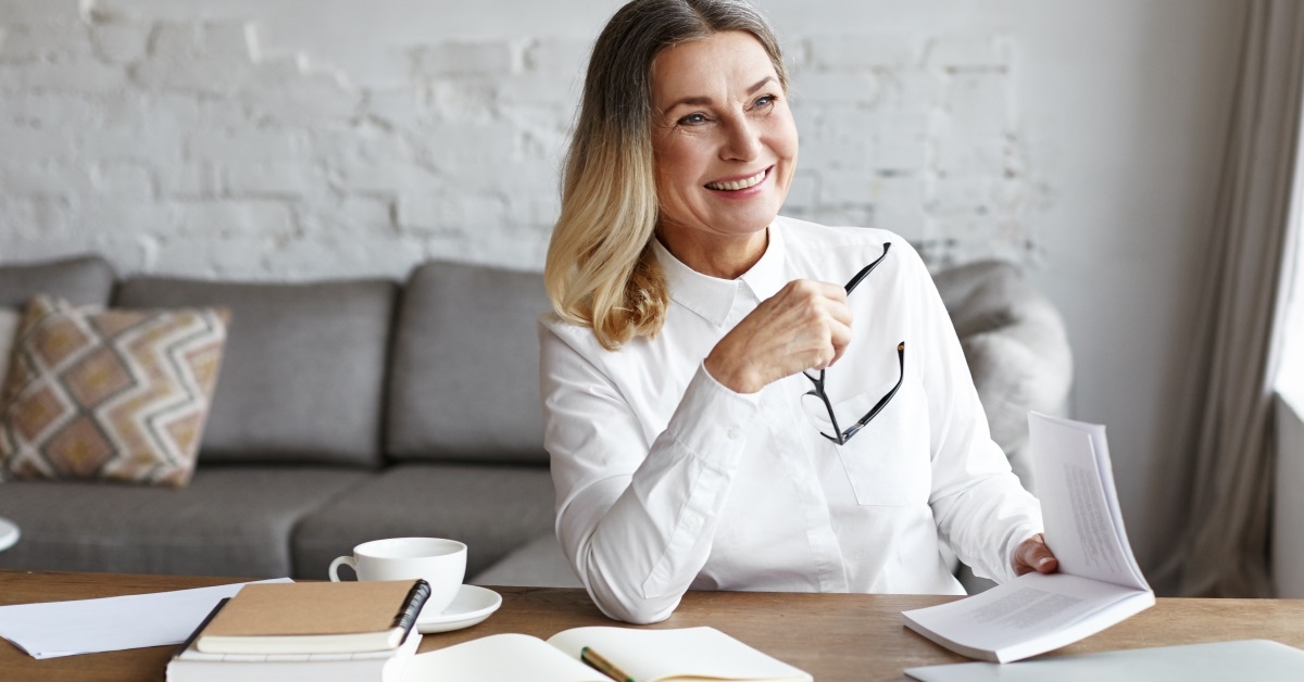 woman holding a pair of glasses and a book in her hand