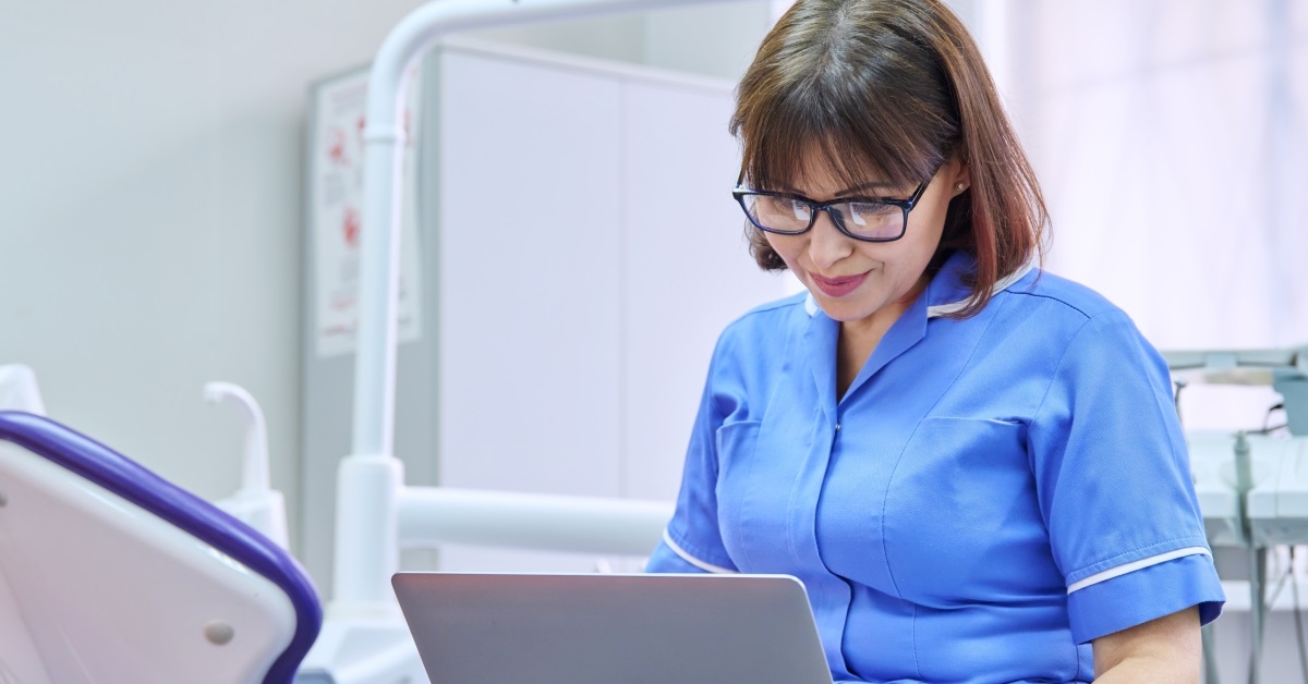 nurse sitting in dental clinic using laptop