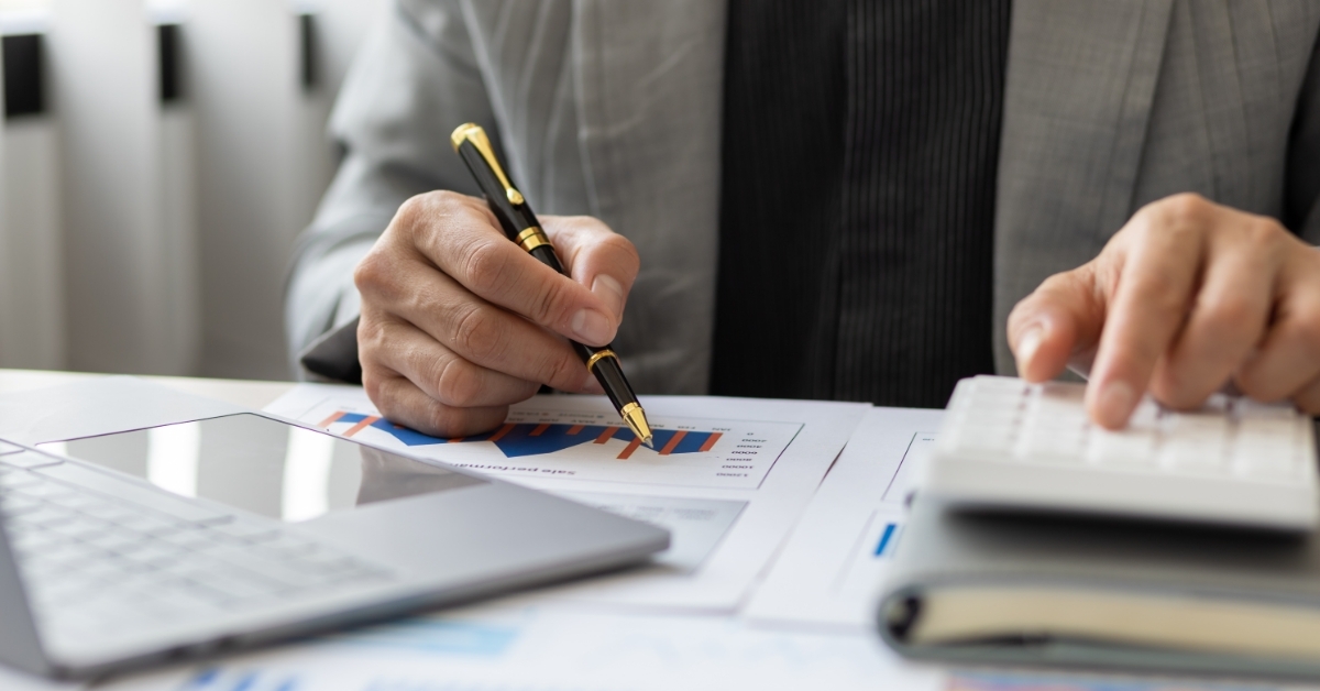 financial advisor in suite using calculator while writing on notepad