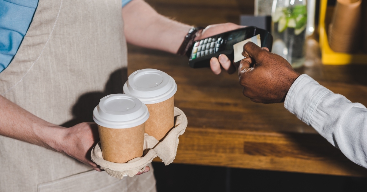barista with terminal and coffee cups in hands