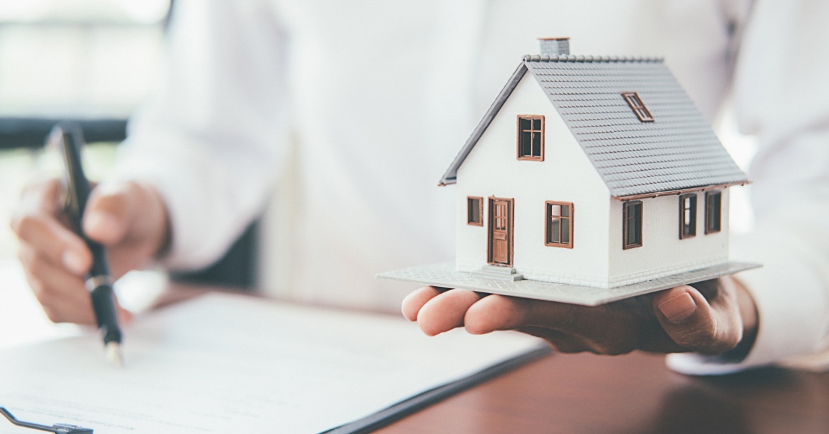 holding house model while writing on notepad