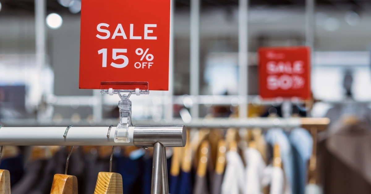 store with cloth racks having 15% off sale sign on them