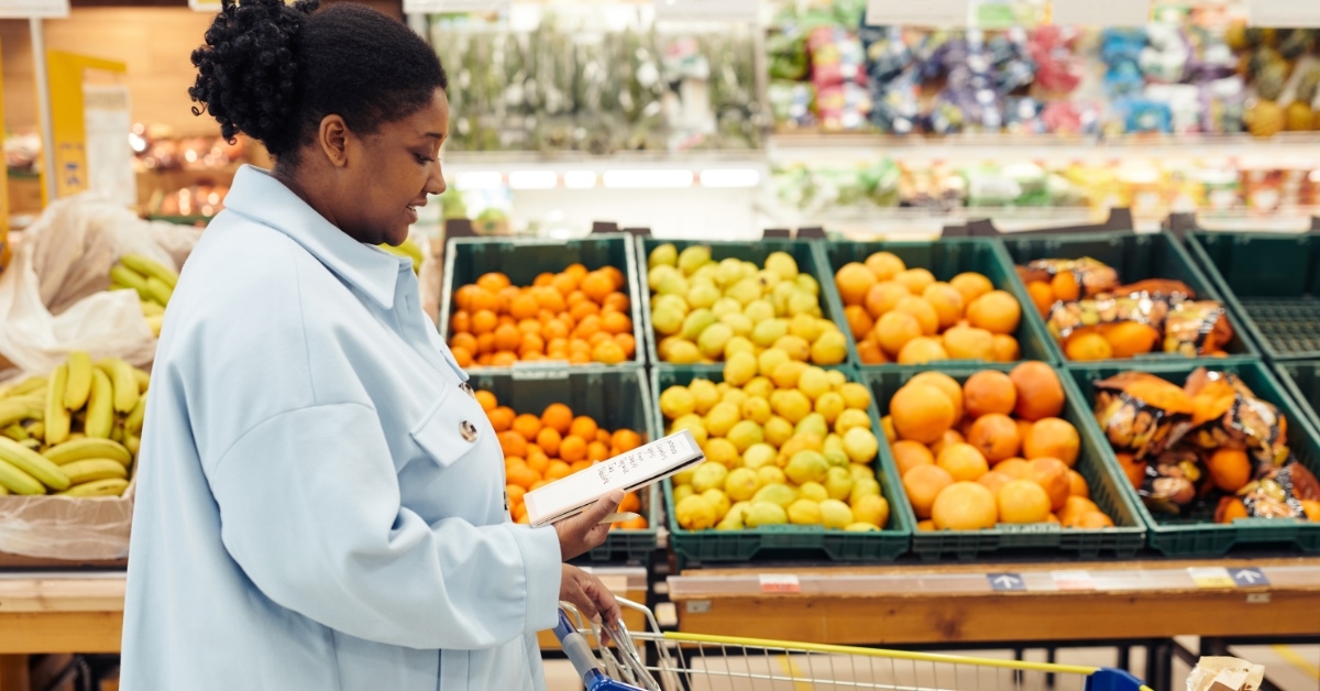 african american woman reviewing grocery list at store while driving cart