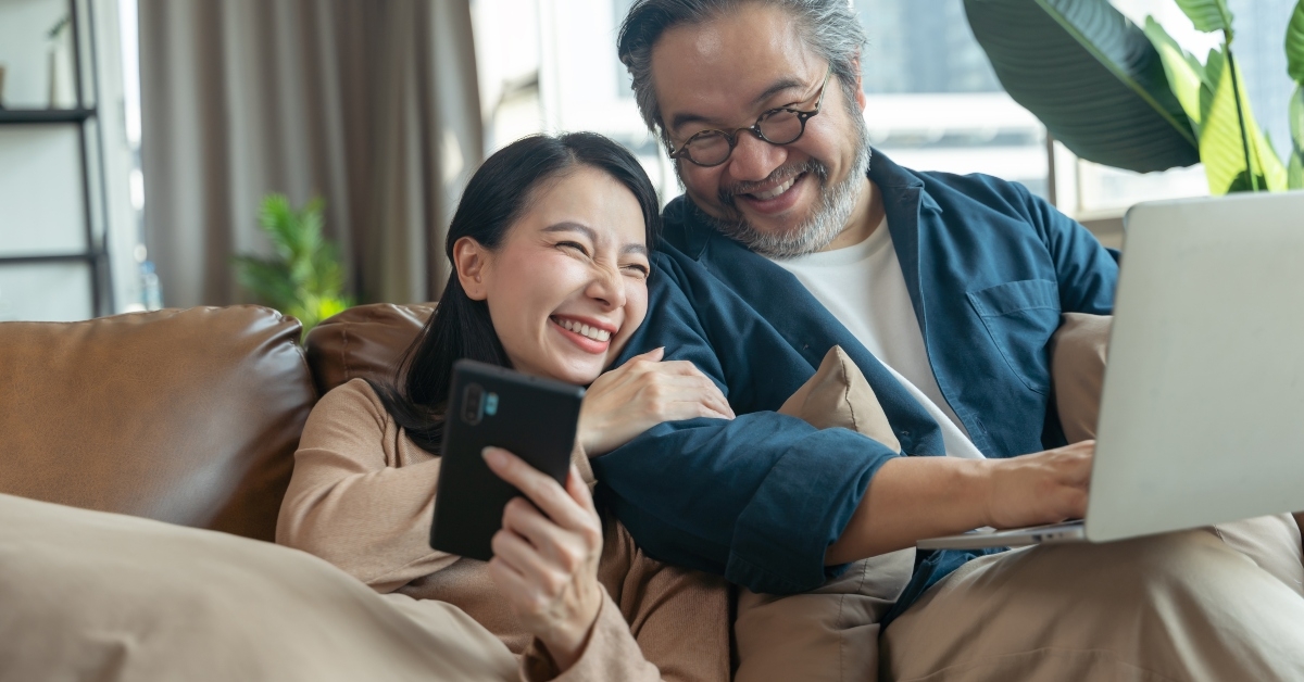 wife showing smartphone to husband in living room