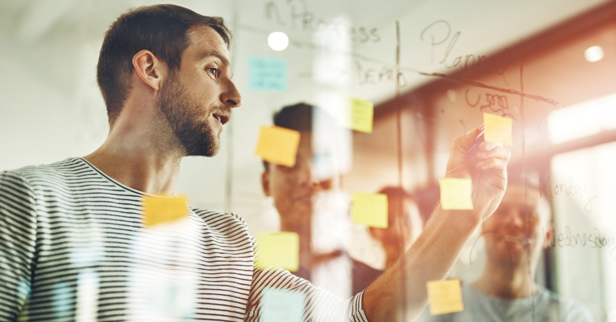 colleagues discussing over sticky notes on glass