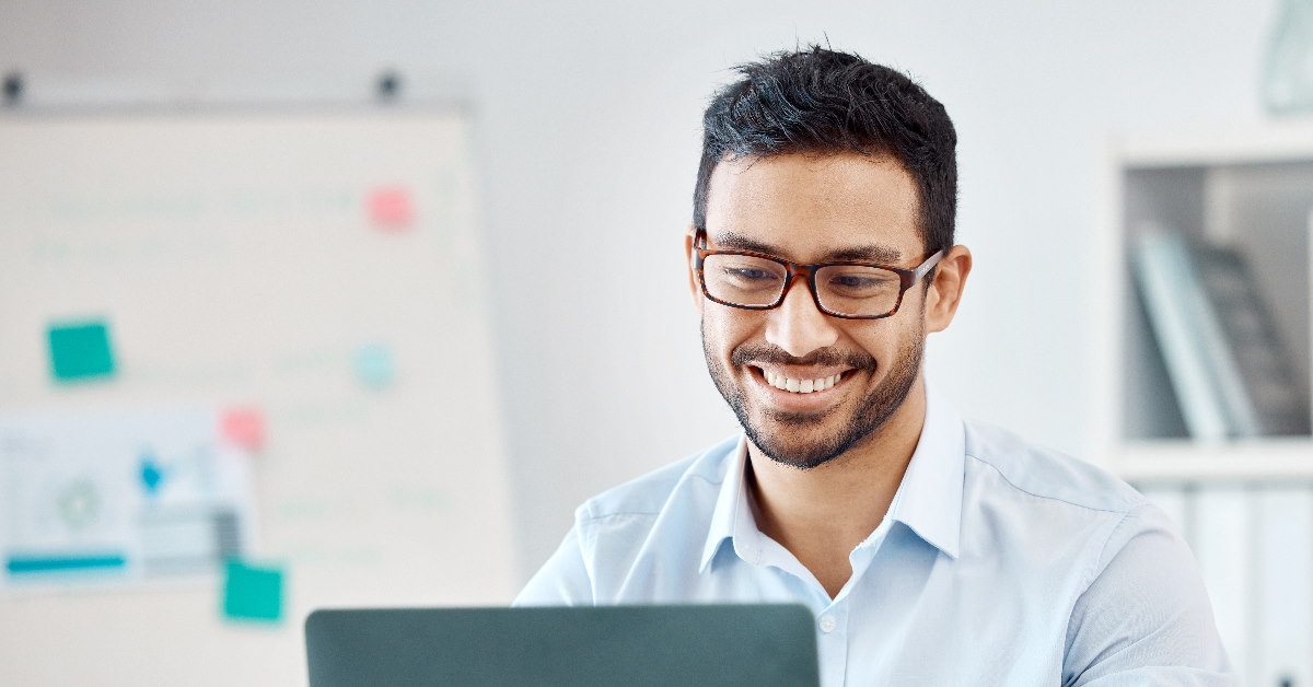 man wearing glasses while using laptop on table