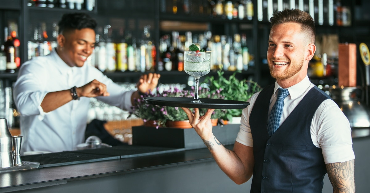 smiling waiter holding a cocktail