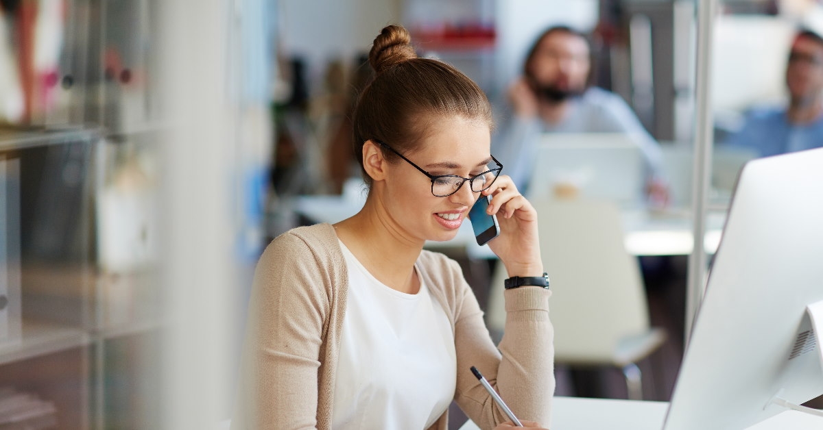 woman working in office talking on smartphone
