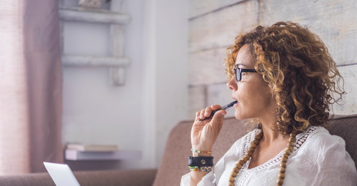 woman with laptop on lap thinking about something 