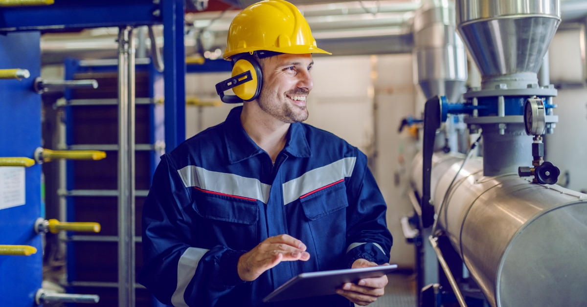 worker in yellow hat checking boiler at factory